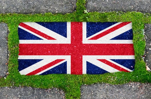 Ecological concept. On the sidewalk in green moss, paving slabs with the image of the flag of Great Britain.