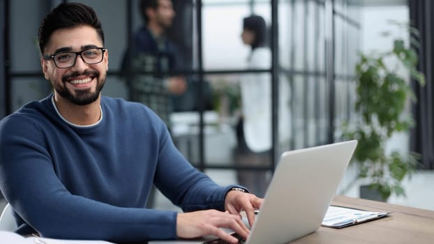 Portrait of young man sitting at his desk in the office