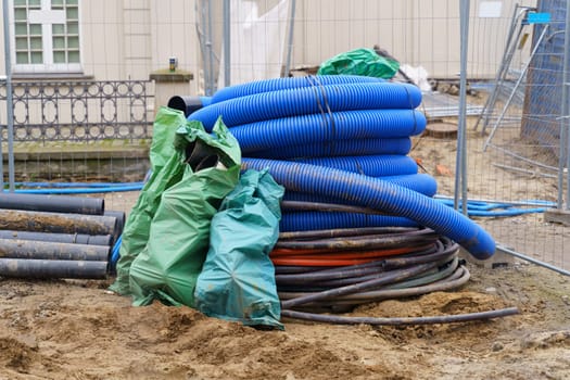 Blue corrugated and black pipelines of various diameters lie on a construction site on the street. Repair of communications.