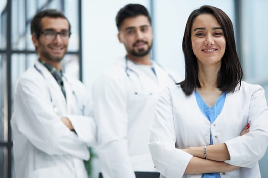 Attractive female doctor in front of the medical staff in the hospital stands with her arms crossed