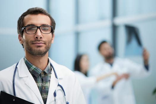Confident doctor posing with, he is smiling at camera