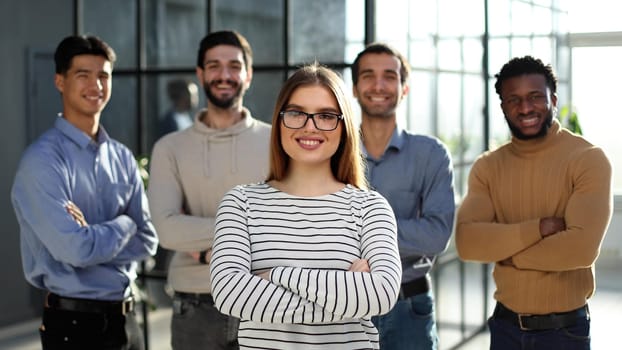 Portrait of business woman and colleagues standing with their arms crossed in the office