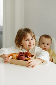 Portrait of a girl in a dressing gown who sits in the kitchen and holds a box of fruit candy in her hands.