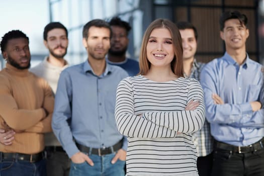 Smiling businesswoman looking at camera together with colleagues in the background