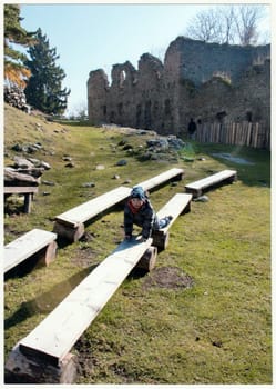 THE CZECHOSLOVAK REPUBLIC - CIRCA 1990s: Retro photo shows small boy in front of ancient castle ruins. Boy on an autumn trip. Holiday - vacation trip. Vintage color photography. Circa 1990.