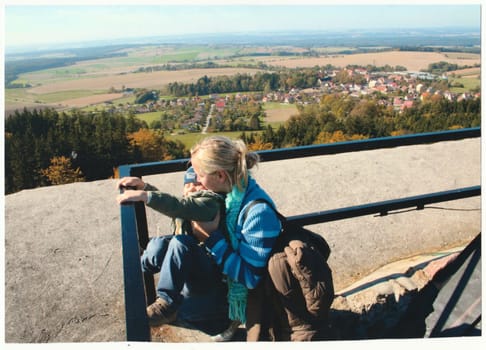 THE CZECHOSLOVAK REPUBLIC - CIRCA 1990s: Retro photo shows mother and son on observation tower lookout. View on autumn landscape. Fall trip. Vintage color photography. Circa 1990.