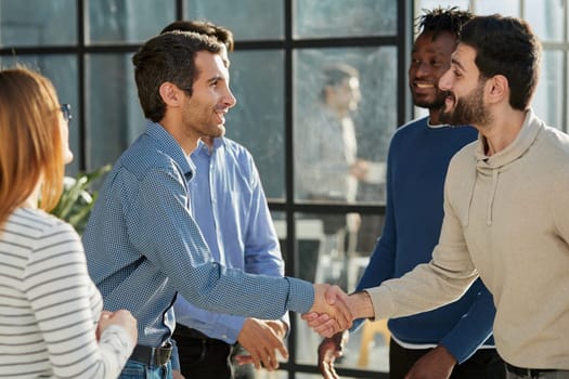 Smiling multiethnic friend getting acquainted in office corridor