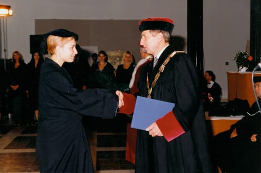 THE CZECHOSLOVAK SOCIALIST REPUBLIC - CIRCA 1980s: Retro photo shows degree ceremony. A chancellor congratulates student on degree graduation. Vintage color photography. Circa 1990.