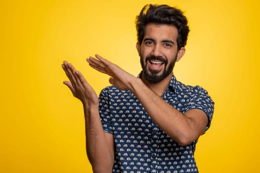 Young indian man showing wasting, throwing money around, more tips, big profit, winning lottery jackpot, successful shopping payment purchase, cashback. Hindu guy isolated on studio yellow background