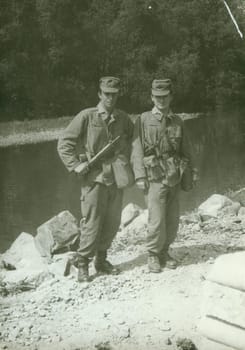 THE CZECHOSLOVAK SOCIALIST REPUBLIC - CIRCA 1970s: Retro photo shows young men - soldiers during army patrol. Soldiers pose at the river bank. Vintage photography. Circa 1970.