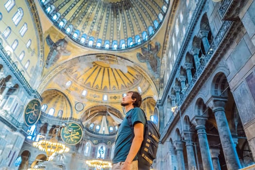 Man tourist enjoying Hagia Sofia, Ayasofya interior in Istanbul, Turkey, Byzantine architecture, city landmark and architectural world wonder. Turkiye.