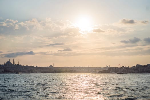 Istanbul at sunset, Turkey. Tourist boat sails on Golden Horn in summer. Beautiful sunny view of Istanbul waterfront with old mosque. Concept of travel, tourism and vacation in Istanbul and Turkey. Turkiye.