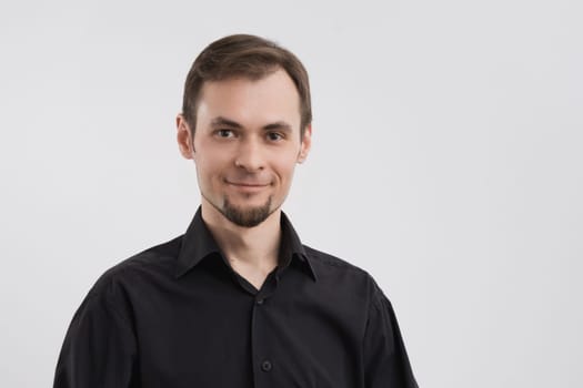 Caucasian calm smiling man 30s in a black shirt portrait on white background.