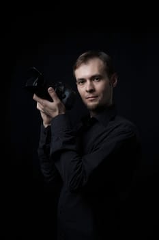 Low key portrait of photographer man with a photo camera in the dark, copy space.