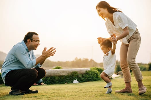 Portrait of a loving family spending quality time in nature, teaching their baby girl to walk on a beautiful spring day. childhood parent care support concept