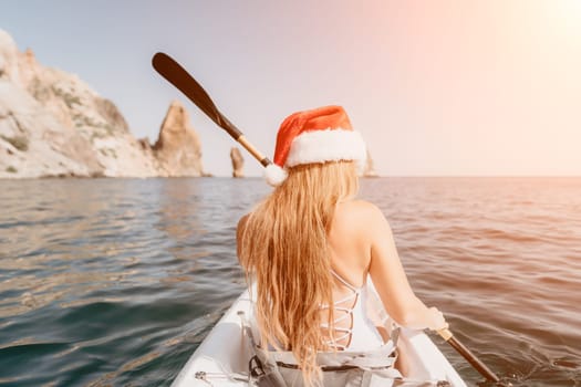 Woman in kayak back view. Happy young woman with long hair floating in transparent kayak on the crystal clear sea. Summer holiday vacation and cheerful female people relaxing having fun on the boat