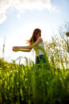 cute woman in summer clothes standing in a field of tall grass, bottom view. High quality photo