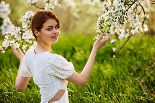 Portrait of a beautiful woman looking at the camera touching the flowers of an apple tree. High quality photo