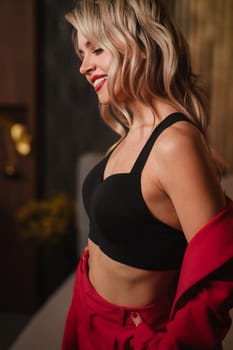 a beautiful girl dressed in a red formal suit posing in a modern interior.