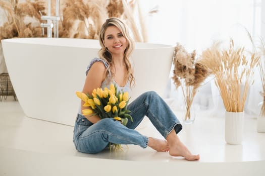 Cute smiling girl with a bouquet of yellow tulips in the interior.