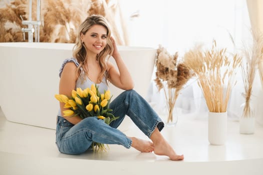 Cute smiling girl with a bouquet of yellow tulips in the interior.