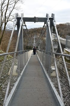 Vertical back view of people walking on the Titan RT giant suspension bridge in the Harz Mountains