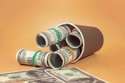 An arrow made of dollar bills points to a paper cup stuffed with wads of money.