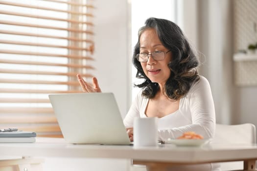 Modern mature businesswoman having online video call conference on laptop. Distant communication, remote work concept.