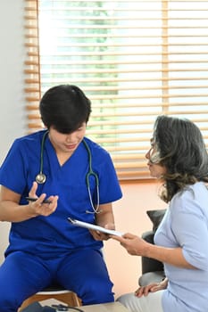 Male health visitor consulting middle age woman during home visit. Elderly healthcare and Home health care service concept.