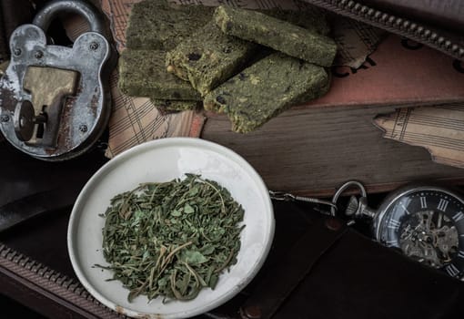 Bangkok, Thailand - Mar 17, 2023 : Homemade Cannabis Snack Sticks on the Old Music Notebook with the Chopped Cannabis leaves in the Small Iron Plate besides the Analog Pocket Watch and Vintage Iron Padlock. The Concept of Relaxation and the Happiness, Vintage style, Space for text. No focus, specifically.