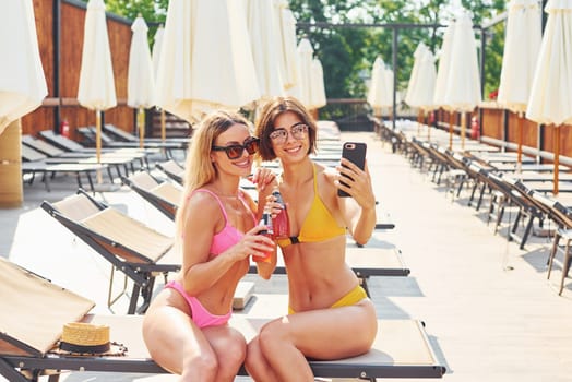 Friends have good time. Women in swimsuits have fun outdoors together at summertime.