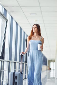 Woman holding coffee. Young traveler is on the entrance hall in the airport.