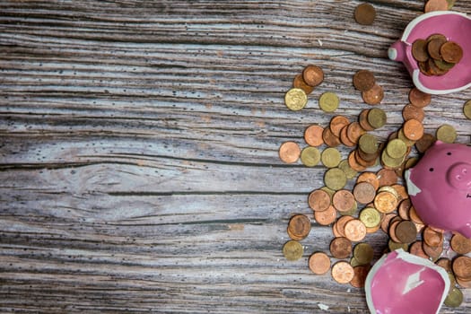 Broken piggy bank smashed into pieces with hammer, with cash and coins on wooden background top view with copy space, money savings concept space for text