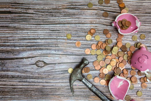 Broken piggy bank smashed into pieces with hammer, with cash and coins on wooden background top view with copy space, money savings concept space for text