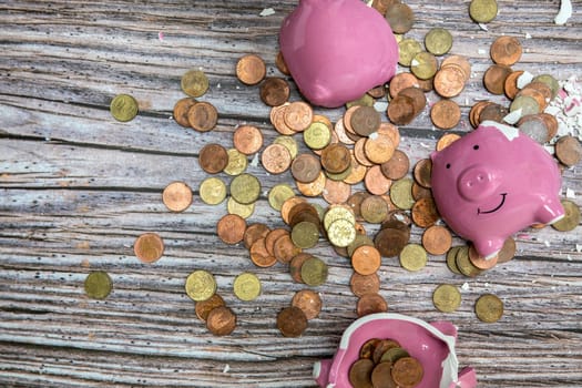 Broken piggy bank smashed into pieces with hammer, with cash and coins on wooden background top view with copy space, money savings concept space for text