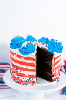 Slicing July 4th chocolate cake decorated with red, white, and blue buttercream frosting.