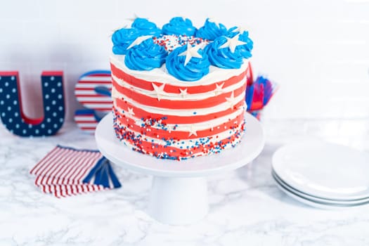 Decorating chocolate cake with white, red, and blue buttercream frosting for July 4th celebration.