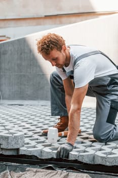 Sitting outdoors. Young man working in uniform at construction at daytime.