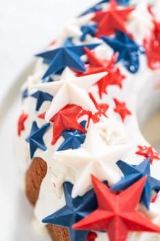 July 4th bundt cake covered with a vanilla glaze and decorated with chocolate stars on a white plate.