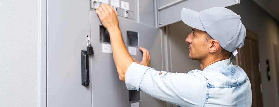 Young smiling electrician doing his work. electrical panel.