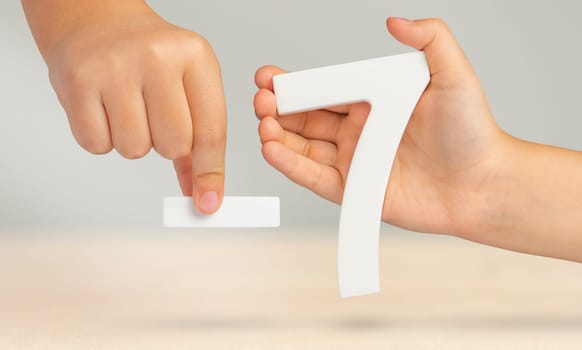 Minus seven. The number seven and the minus symbol in a hand close-up on a light gray background. The concept of removal or taking away.