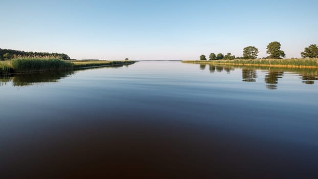 River and lagoon delta, wide smooth water and a quiet summer evening