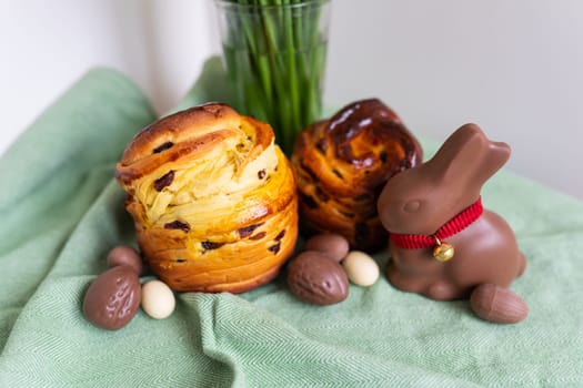 Homemade Easter traditional pastries lie on a green napkin with a bouquet of flowers, a rabbit, chocolate eggs. Easter baking and decoration