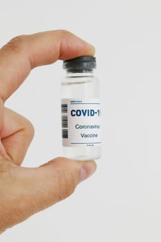 Close-up of a hand holding a bottle of covid-19 vaccine.