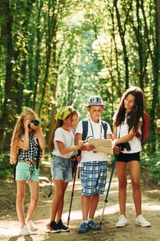 Weekend activies. Kids strolling in the forest with travel equipment.
