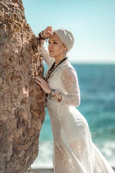 Middle aged woman looks good with blond hair, boho style in white long dress on the beach decorations on her neck and arms