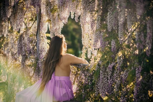 Woman wisteria lilac dress. Thoughtful happy mature woman in purple dress surrounded by chinese wisteria.