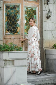 a woman in a flower dress opens the door to the house.