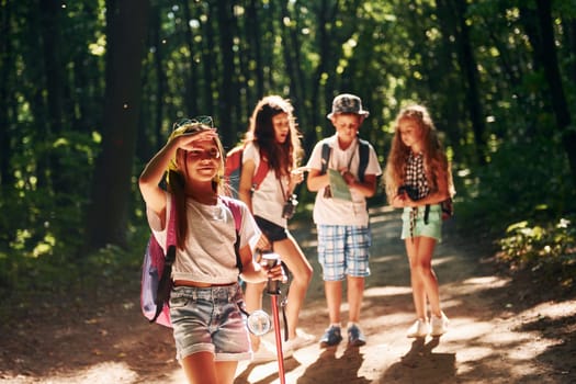 Girl looking far away. Kids strolling in the forest with travel equipment.