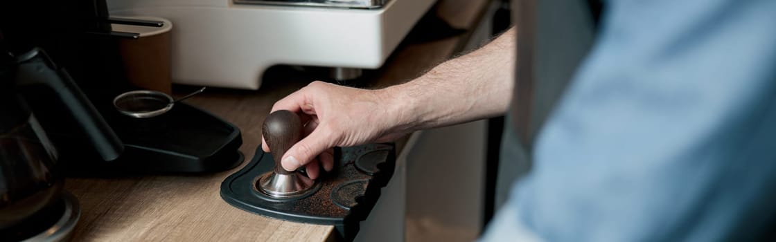 Close up of barista hand holding tamper standing behind a counter